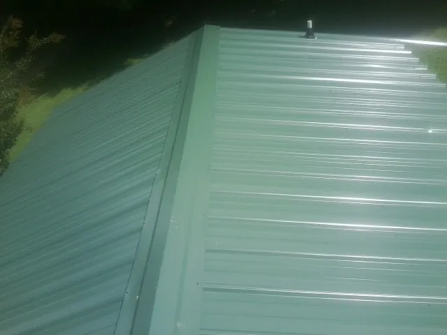 New green metal panels meeting at the ridge of a roof — Flat Roof Repair work by our crew in Danielsville