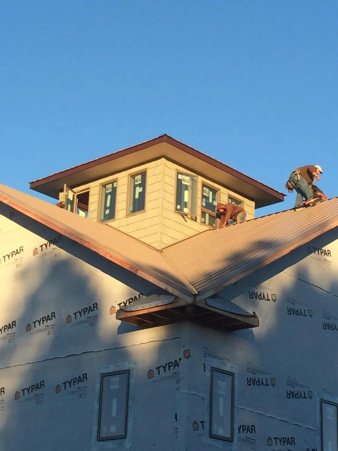 Roofers working around a rooftop cupola on a new metal roof at sunset — Roof Waterproofing in Danielsville by Roofing Brothers